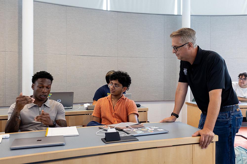 Matt Laszlo'92 speaks with two students in his marketing class.